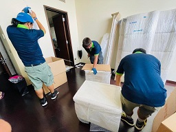Movers carefully wrapping kitchenware in packing paper.
